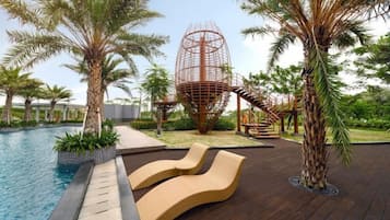 A pool area with lounge chairs, palm trees, and a unique spherical structure.