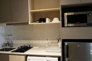 A kitchen with a stainless steel refrigerator, a microwave, and a dishwasher. - Gold Coast Pik Atlantic Sea View Apartment Minimum 2 Nights Stay (North Jakarta)