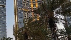 A tall building with a modern design, featuring a series of balconies and a prominent vertical light strip. - Gold Coast Pik Atlantic Sea View Apartment Minimum 2 Nights Stay (North Jakarta)