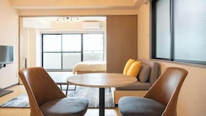 A modern hotel room with a sofa, two armchairs, a round table, and a TV. - Raiwa Mansion Minami Azabu (Tokyo)
