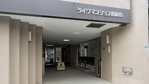 A building entrance with a sign in Japanese, a tiled floor, and a fire extinguisher. - Raiwa Mansion Minami Azabu (Tokyo)