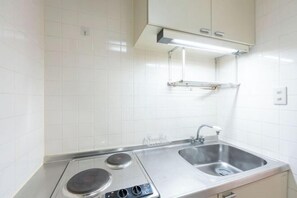Una cocina moderna con paredes de azulejos blancos, electrodomésticos de acero inoxidable y un lavamanos doble.