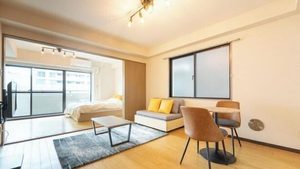 A modern living room with a sofa, chairs, a coffee table, and a large window. - Raiwa Mansion Minami Azabu (Tokyo)