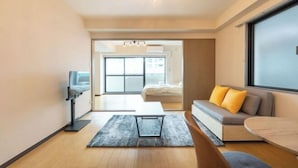 A modern living room with a sofa, a coffee table, a TV, and a large window. - Raiwa Mansion Minami Azabu (Tokyo)
