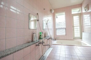 Kylpyhuone, jossa on kylpyamme, suihku ja pesuallas sekä hygieniatarvikkeita.