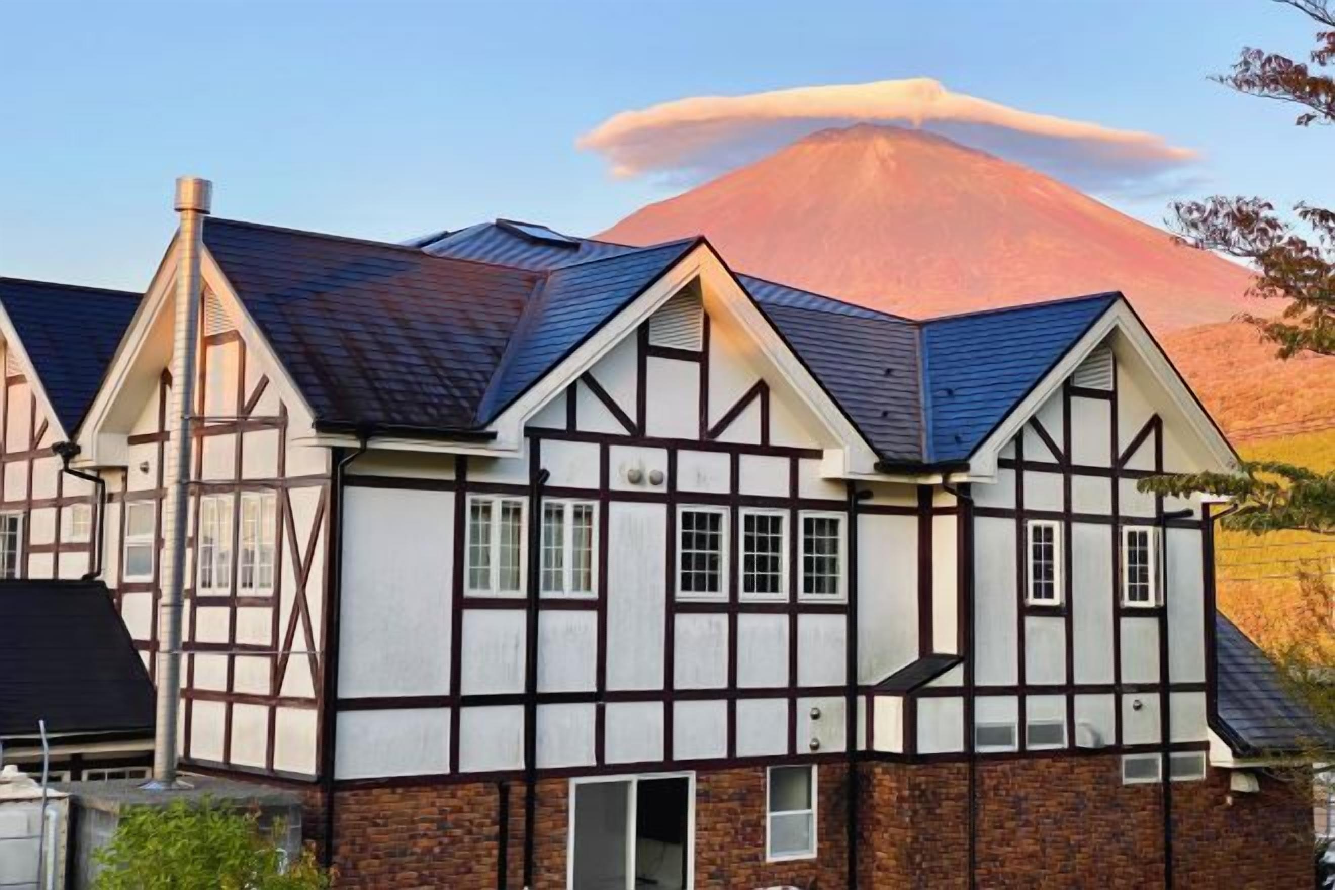 Une maison traditionnelle à colombages, dotée d’un toit à forte pente et d’une cheminée.
