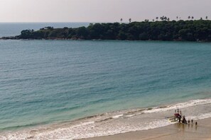 A beach with calm waters, a sandy shore, and a distant tree-covered landmass. - Ranna Beach House - Your own haven by the beach (Hambantota)