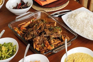 A meal with rice, a glass dish of meat, and side dishes on a wooden table. - Ranna Beach House - Your own haven by the beach (Hambantota)