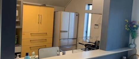 A kitchen with a white countertop, a yellow cabinet, and a white refrigerator.