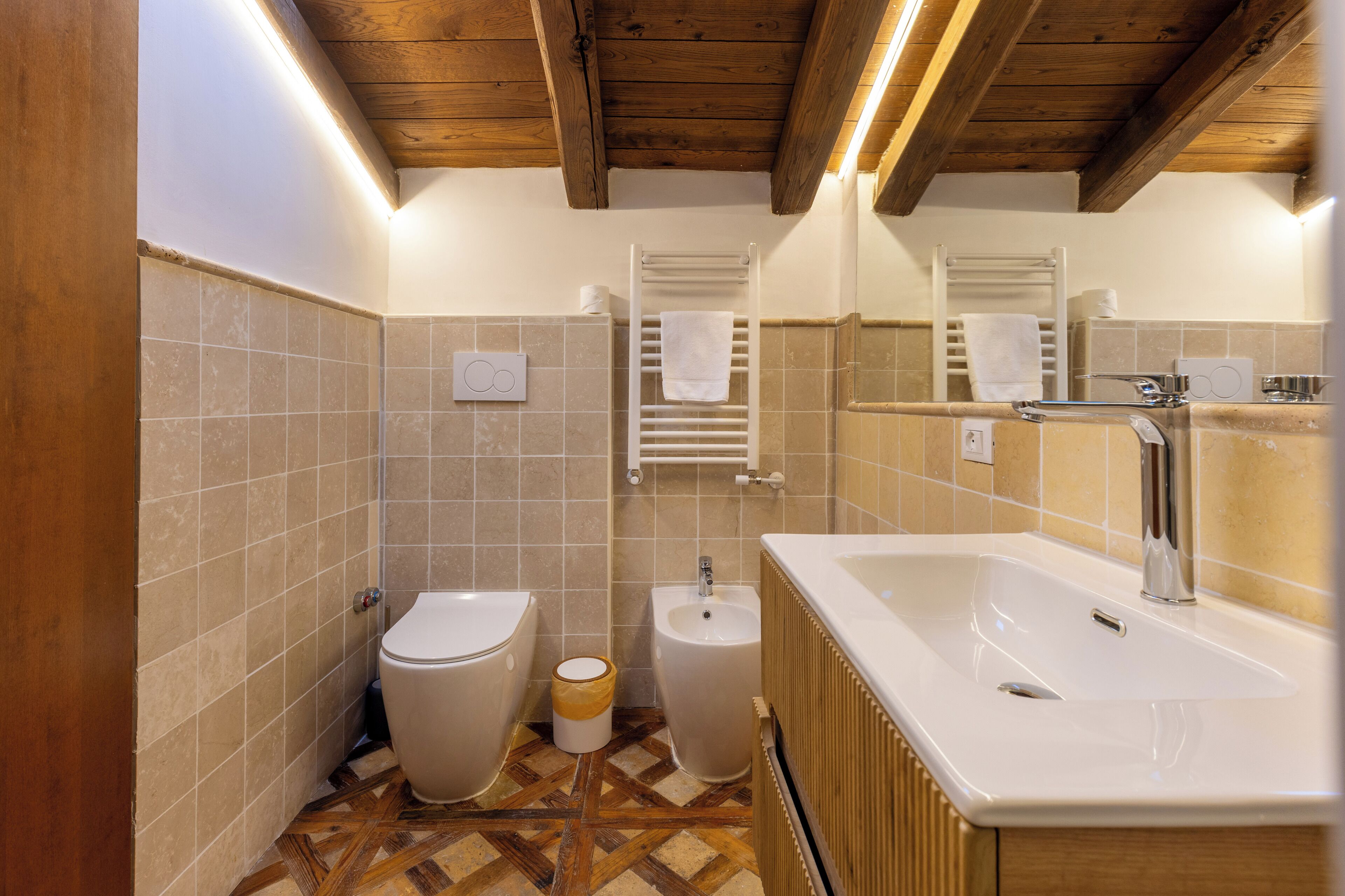 Une salle de bain moderne avec un plafond en bois, un grand lavabo, un bidet et des toilettes.