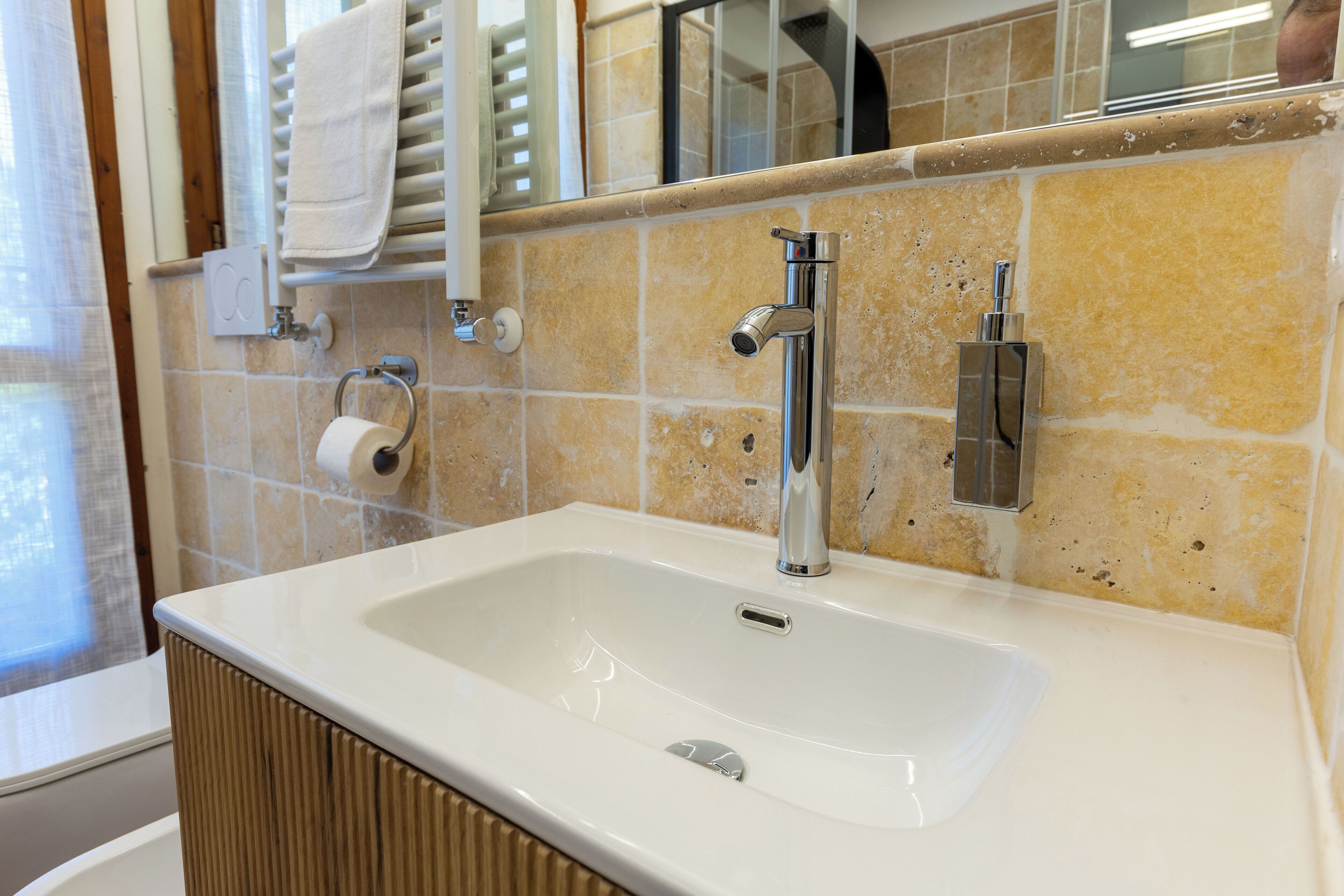 A bathroom with a white sink, a mirror, and a towel rack.