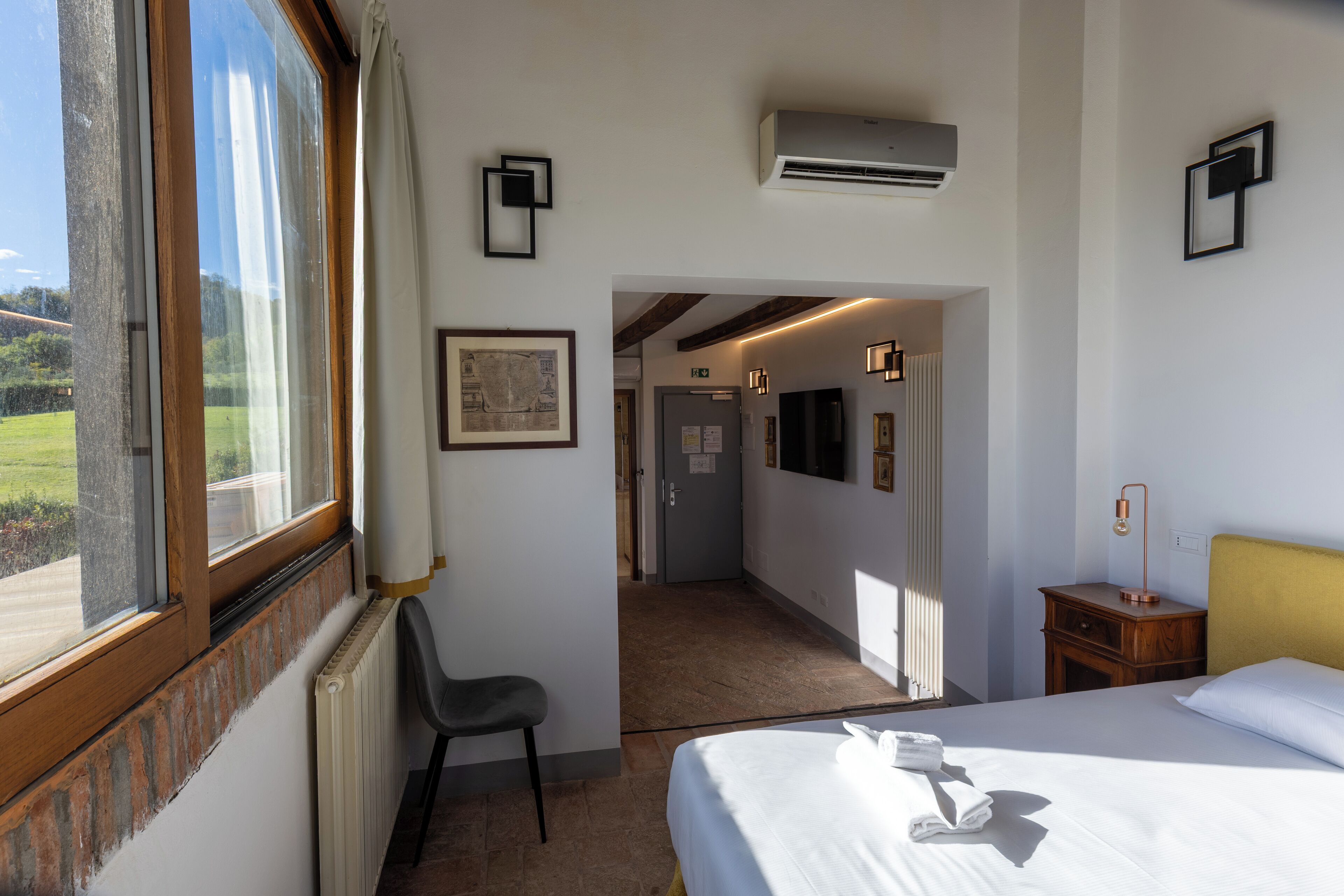 A hotel room with a bed, a chair, a desk, and a view of the outdoors.