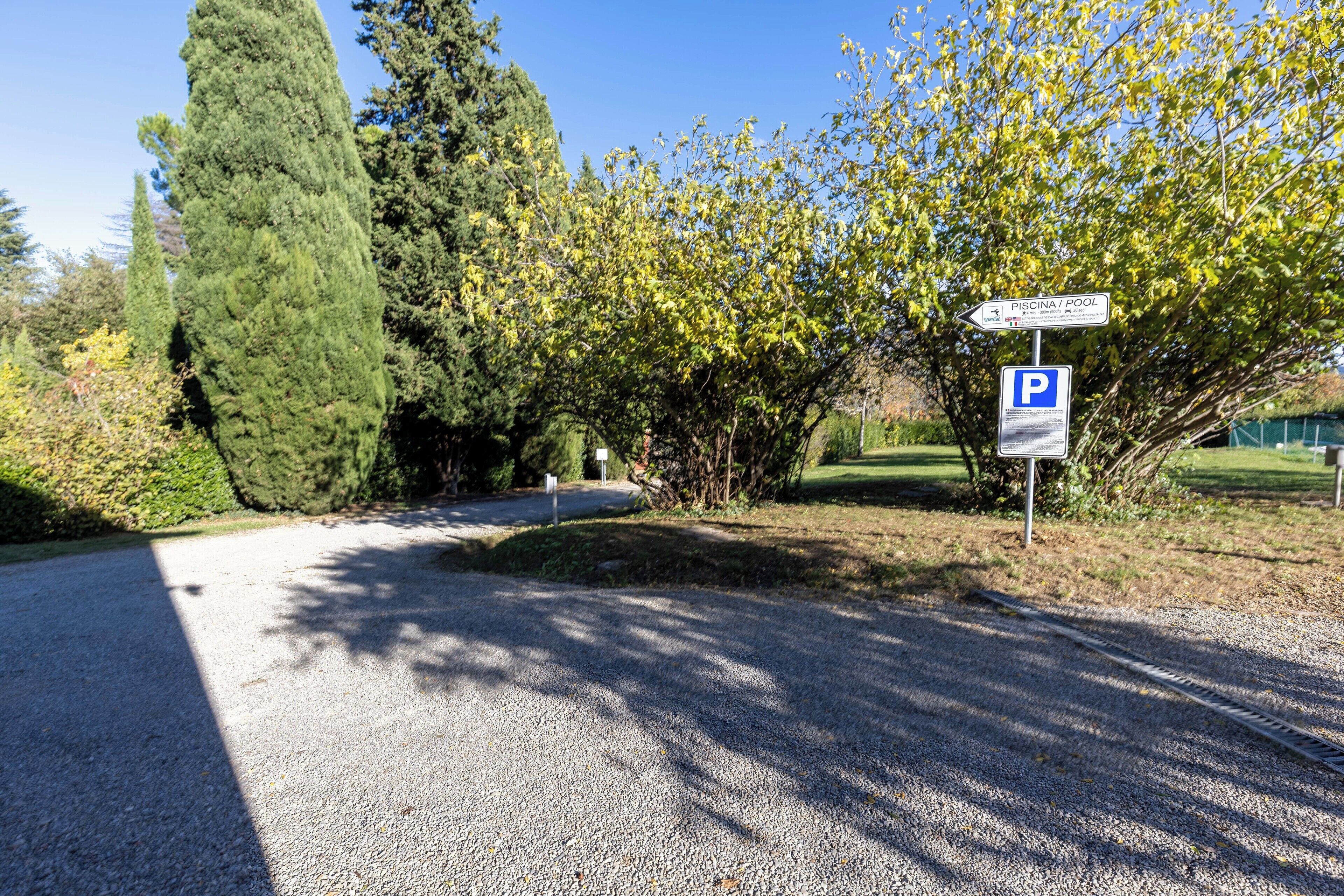 Ein unbefestigter Weg führt zu einem Parkplatz, wo ein Schild auf einen Pool hinweist.