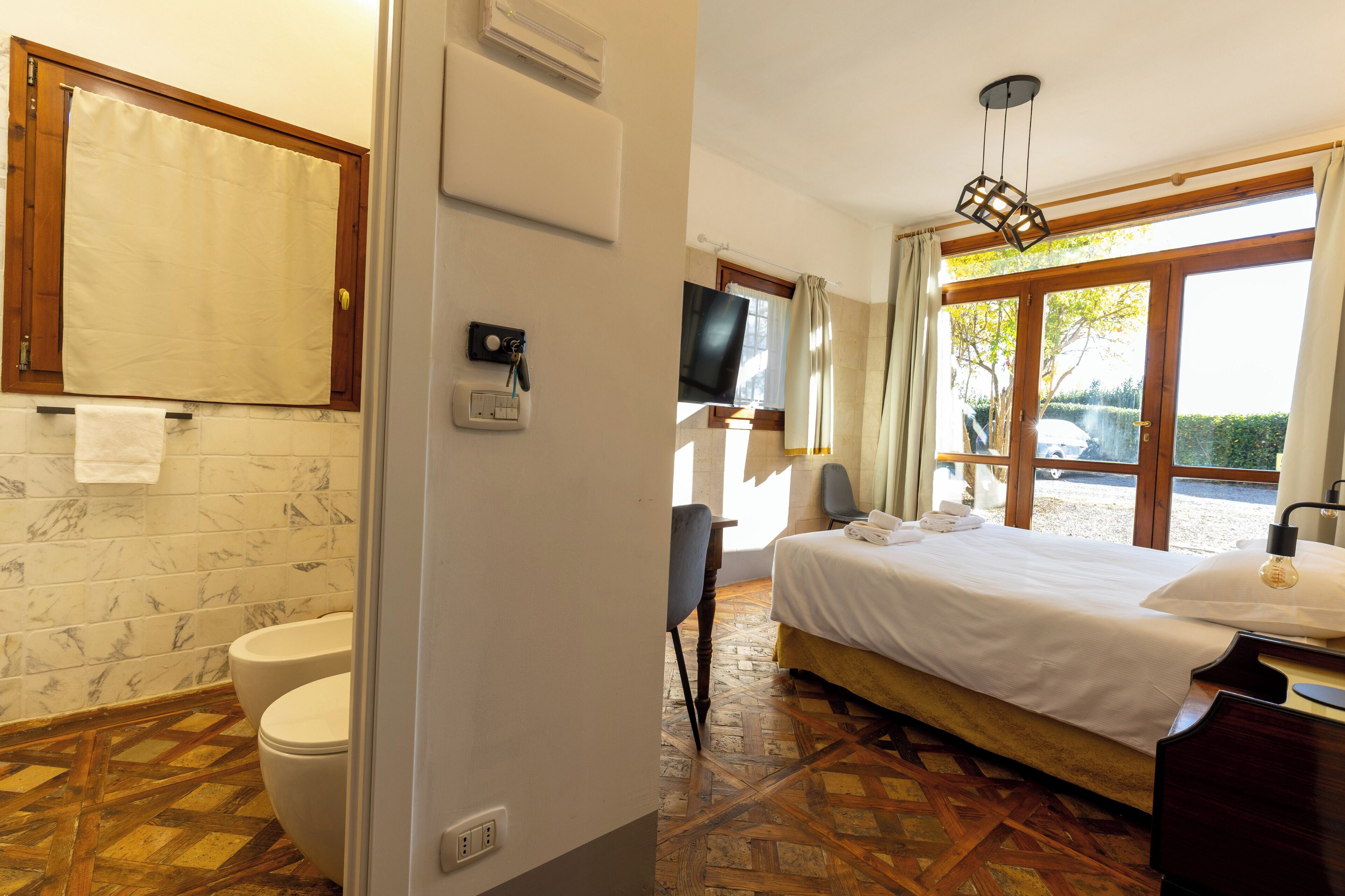 Una habitación de hotel con baño, cama, televisor y vistas al exterior.