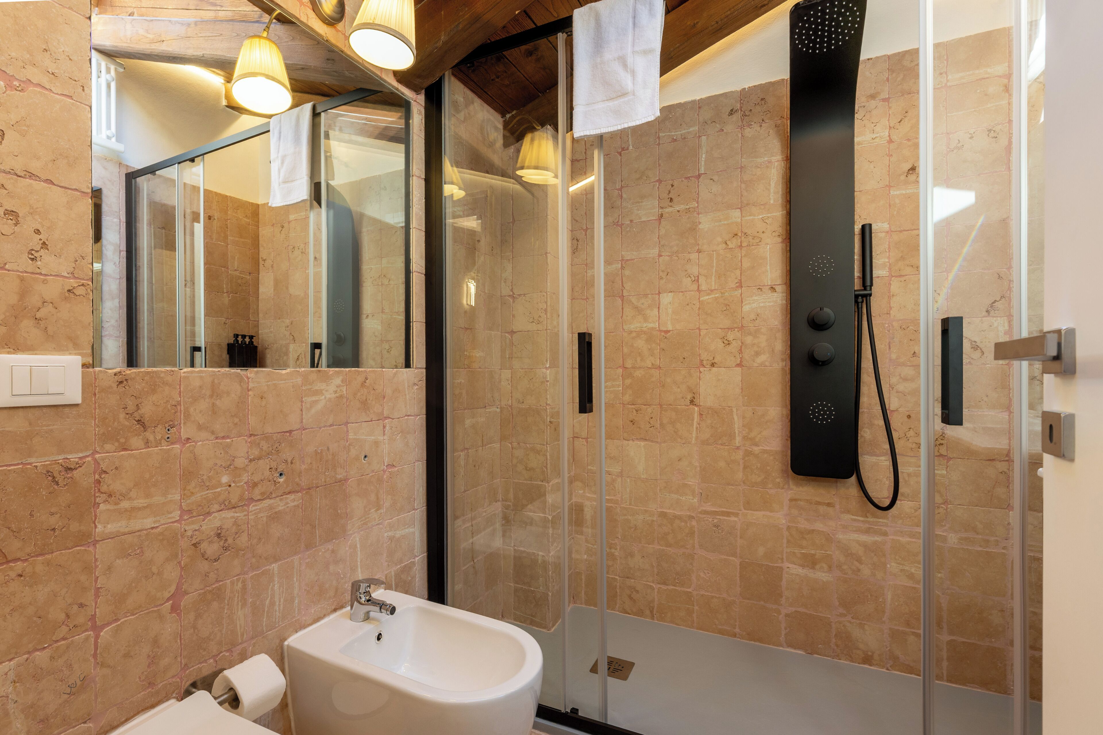 A modern bathroom with a glass-enclosed shower, a white sink, and a mirror.