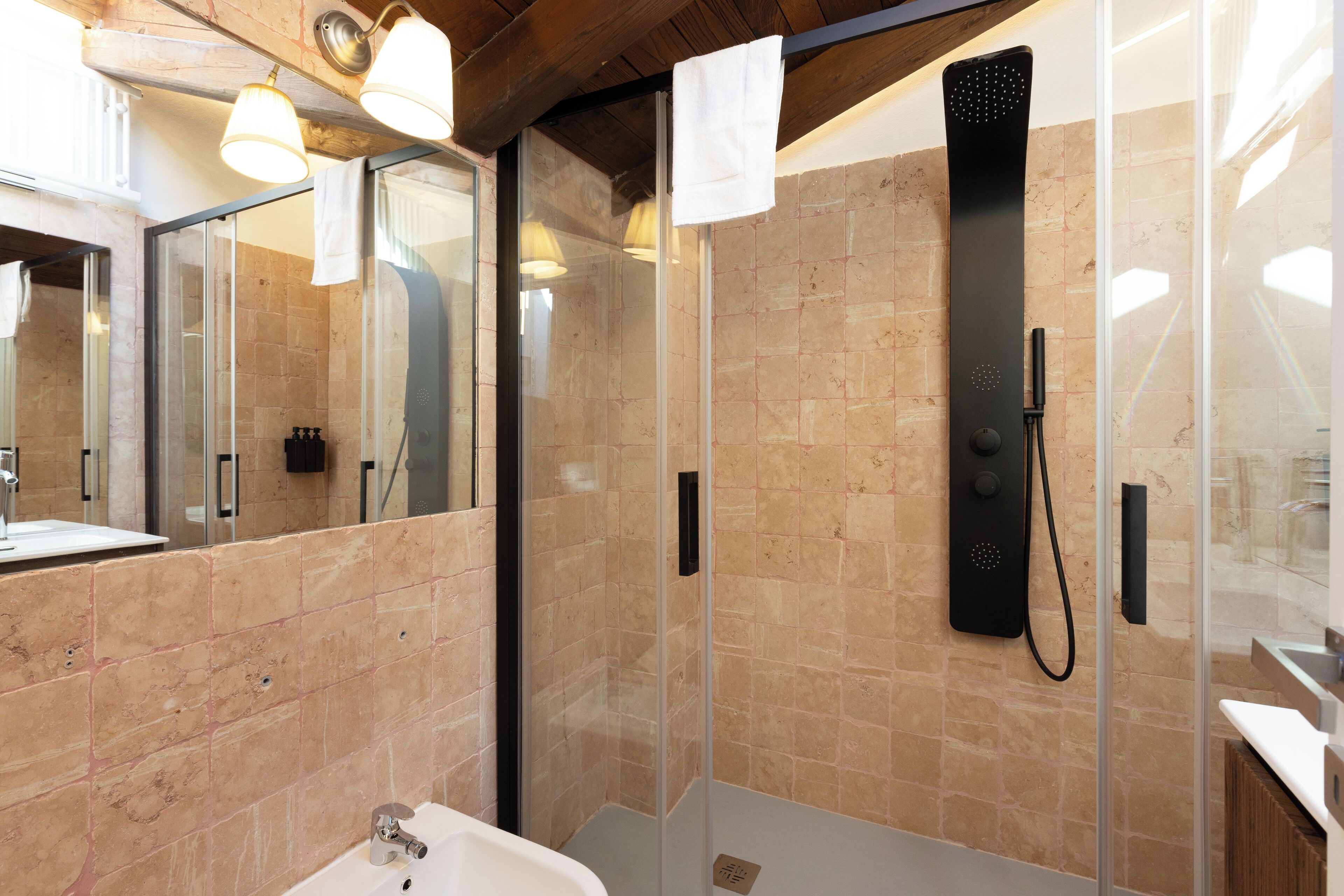 A modern bathroom with a glass shower enclosure, a sink, and a mirror.