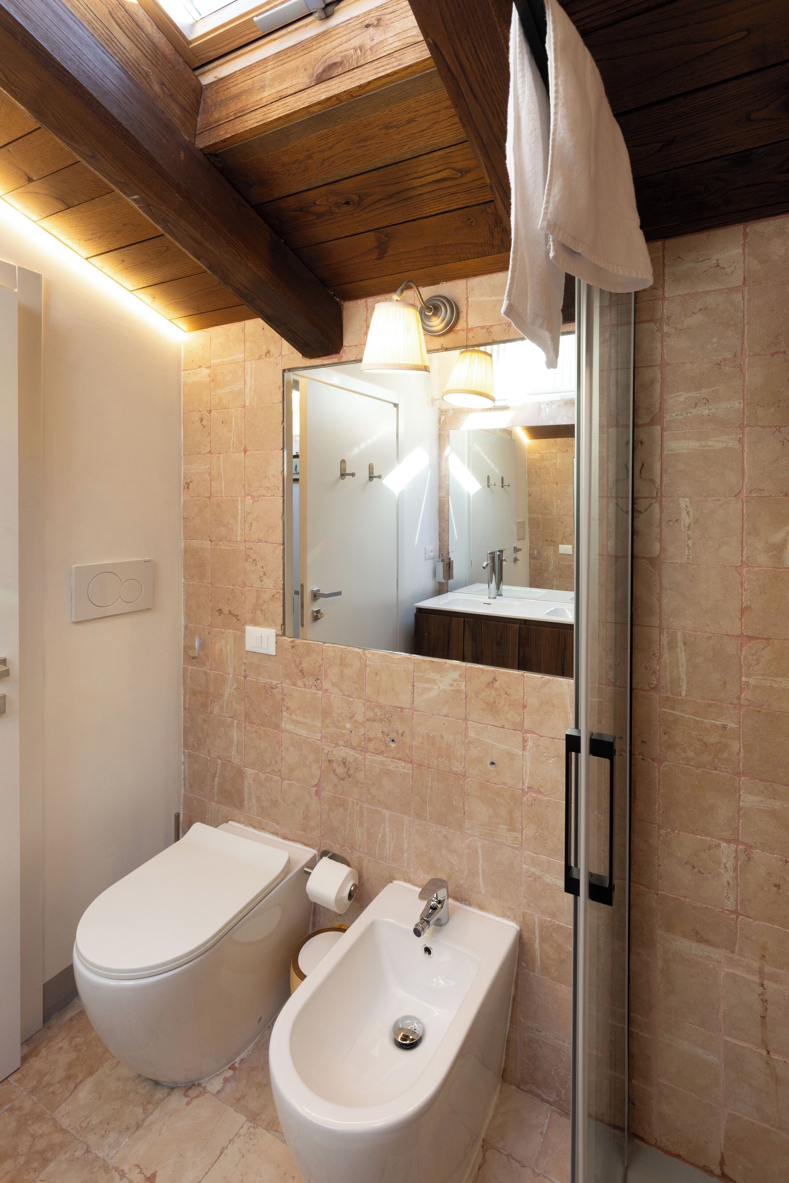 Une salle de bain comprenant des toilettes, un bidet, un lavabo et une douche à parois de verre.