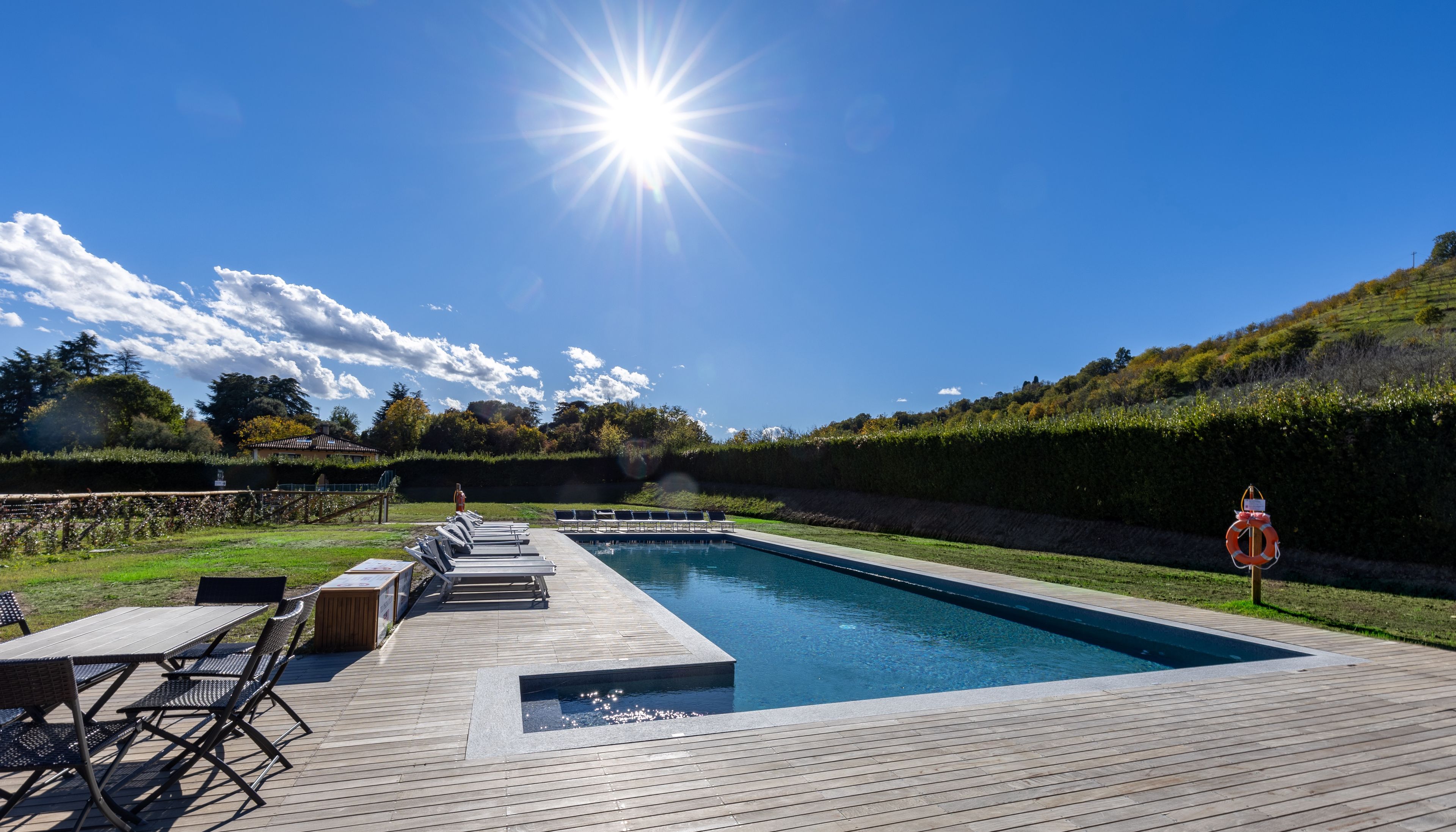 Ein Schwimmbecken mit Holzterrasse, Liegestühlen und einem Rettungsring.