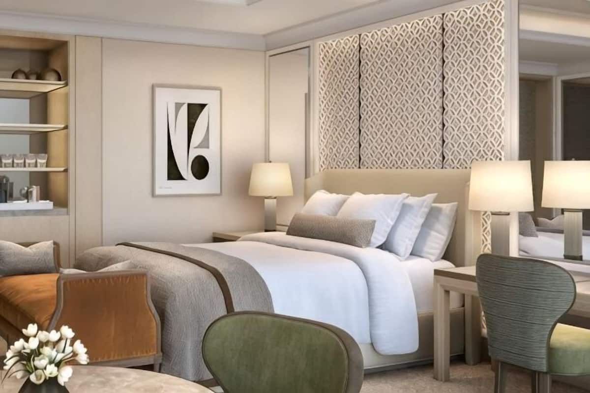 Ein modernes Hotelzimmer mit einem großen Bett, Nachttischlampen, einem Schreibtisch und einem Sessel.