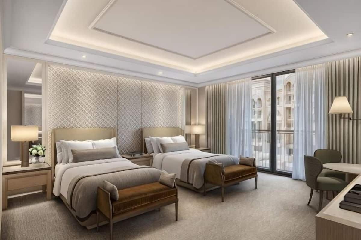 Ein Hotelzimmer mit zwei Betten, einem Schreibtisch, einem Stuhl und Blick auf die Stadt.