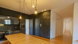 A modern kitchen with a wooden countertop, stainless steel appliances, and pendant lighting. - N Apartments - Luís (Porto)