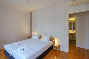 A hotel room with a large bed, bedside tables, a mirror, and a bathroom visible through an open door. - N Apartments - Luís (Porto)