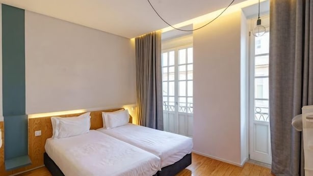 A bedroom with two beds, a window with curtains, and a wooden floor. - N Apartments - Luís (Porto)