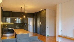 A modern kitchen with a dining area, built-in appliances, and a wooden dining table. - N Apartments - Luís (Porto)