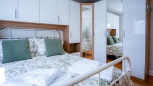 Una camera da letto moderna con un letto, una testiera in legno e un armadio con specchio.