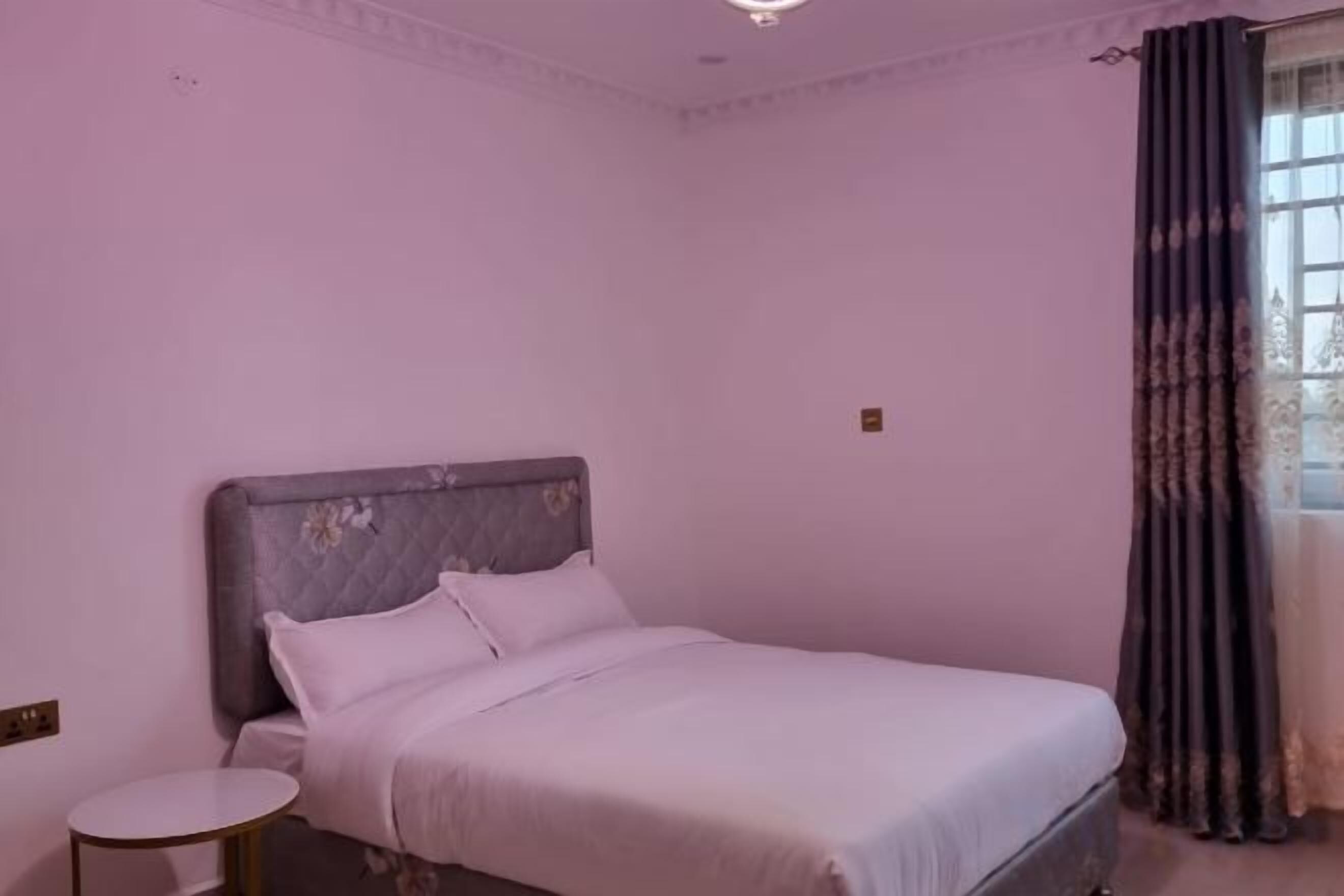 Une chambre à coucher avec un lit, une table ronde et une fenêtre avec des rideaux.