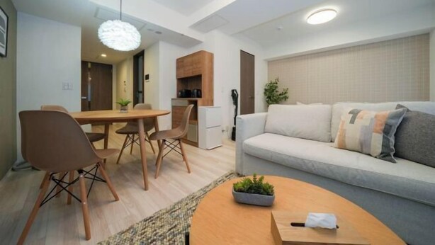 Una sala moderna con sofá, mesa de centro, comedor, sillas y zona de cocina.