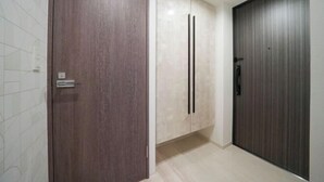 Un pasillo con una puerta de madera, un armario blanco con dos tiradores y una puerta de madera oscura.