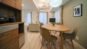 Una cocina moderna con armarios de madera, una mesa de comedor con sillas, una lámpara colgante y un televisor de pantalla plana.