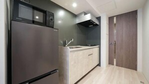 Una cocina compacta con refrigerador, microondas y estufa incorporados, un armario de madera y una puerta de madera oscura.