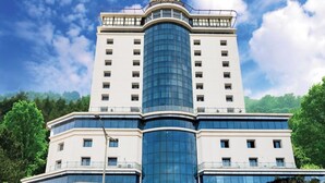 A hotel with a prominent central tower, a ground-level coffee shop, and a restaurant. - Ascot Hotel Calicut (Kozhikode)