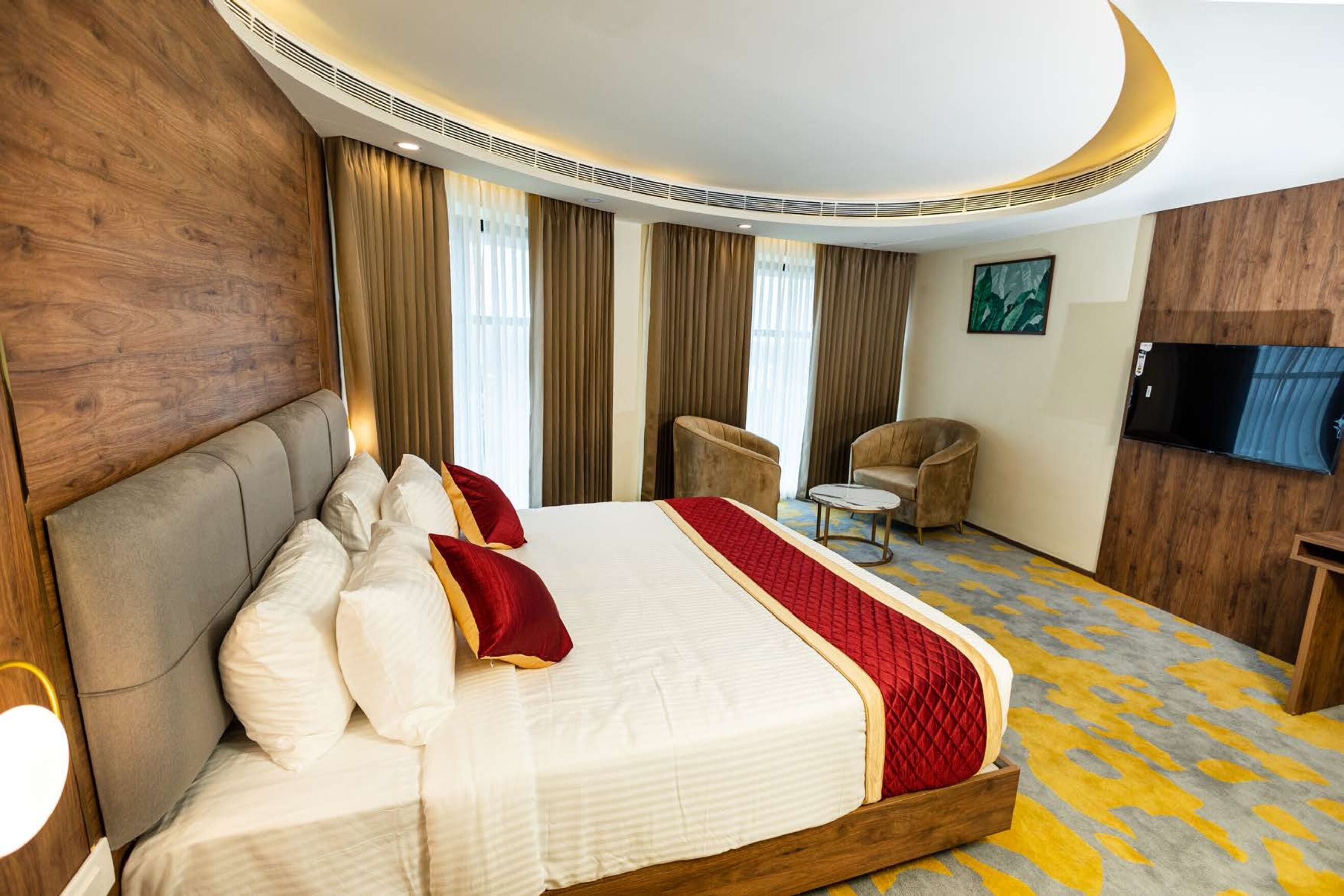 A hotel room with a large bed, a sofa, a TV, and a small table.