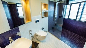 A modern bathroom with a large mirror, two sinks, a toilet, and a shower area. - Ascot Hotel Calicut (Kozhikode)