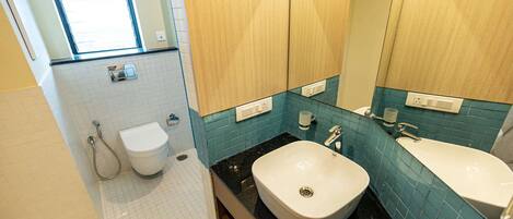 A bathroom with a toilet, bidet, and two sinks with mirrors.