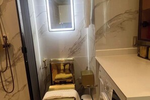 Kylpyhuone, jossa on marmoriseinä, suihku, wc ja pesuallas.