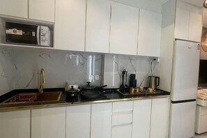 A modern kitchen with white cabinets, a black countertop, and a built-in oven. - Pattaya Jomtien Vitala Luxury Golden Style Hotel Apartment (Next to Airport Bus Station) (Pattaya)