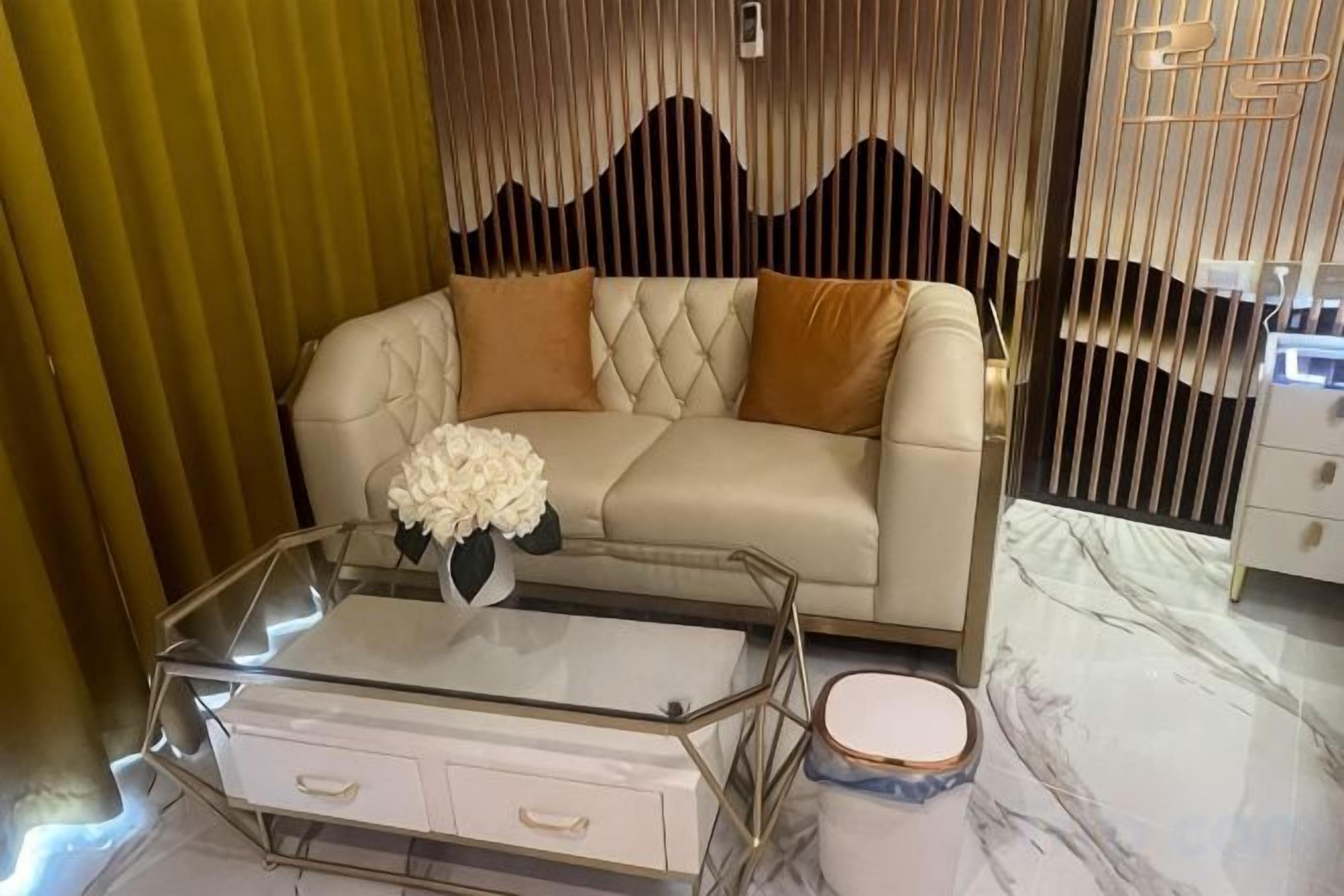 A modern living room with a leather sofa, a glass coffee table with drawers, and a decorative vase.