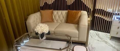 A modern living room with a leather sofa, a glass coffee table with drawers, and a decorative vase.