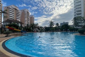 Una piscina con tobogán, rodeada de edificios altos y palmeras.