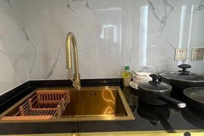 A kitchen with a stainless steel sink, a gold faucet, and black countertops. - Pattaya Jomtien Vitala Luxury Golden Style Hotel Apartment (Next to Airport Bus Station) (Pattaya)