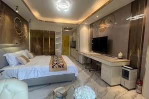 Ein modernes Schlafzimmer mit Bett, Nachttisch, Fernseher und einem Schreibtisch.