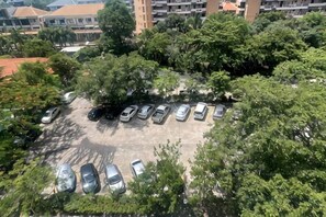 A parking lot with several cars, surrounded by trees and buildings. - Pattaya Jomtien Vitala Luxury Golden Style Hotel Apartment (Next to Airport Bus Station) (Pattaya)