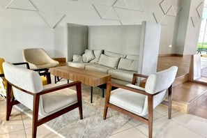 A modern living room with a sofa, two armchairs, a coffee table, and a geometric wall design. - KL Central 31st floor KLCC view (Kuala Lumpur)
