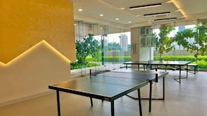 A modern indoor space with ping pong tables, glass walls, and a view of greenery. - KL Central 31st floor KLCC view (Kuala Lumpur)