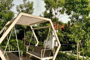 A hexagonal outdoor seating area with a roof, surrounded by lush greenery. - KL Central 31st floor KLCC view (Kuala Lumpur)