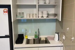 A kitchen with a sink, a kettle, and a shelf with dishes. - KL Central 31st floor KLCC view (Kuala Lumpur)